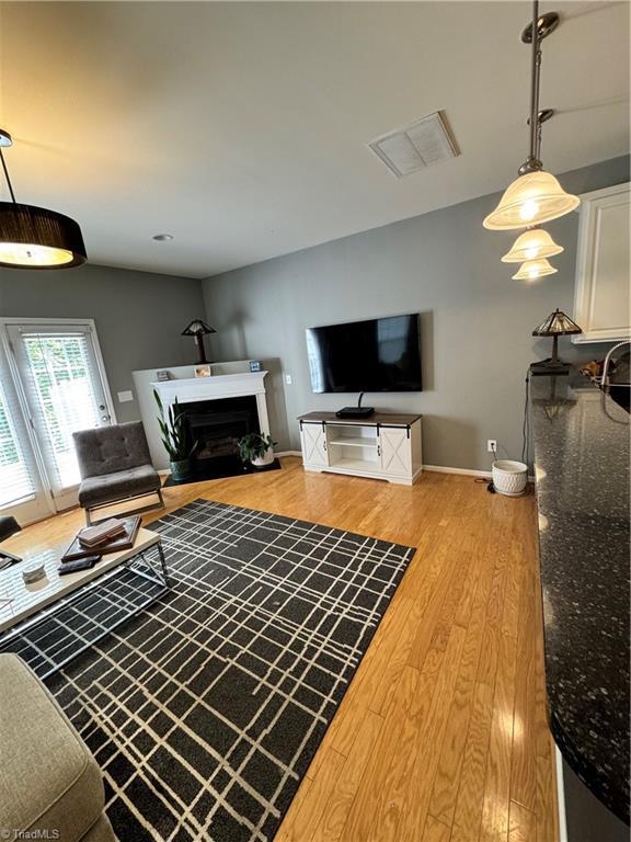 7213 Olmstead Dr, Burlington, NC 27215 - living room featuring light wood-style floors, a fireplace, and baseboards