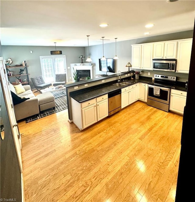7213 Olmstead Dr, Burlington, NC 27215 - kitchen with appliances with stainless steel finishes, a sink, a peninsula, open floor plan, and light wood-type flooring
