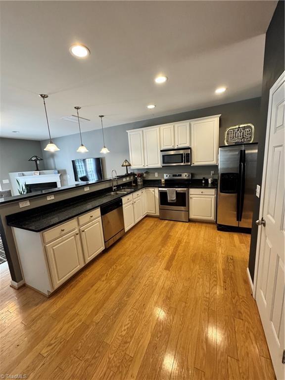 7213 Olmstead Dr, Burlington, NC 27215 - kitchen with stainless steel appliances, a peninsula, light wood-style flooring, dark countertops, and recessed lighting