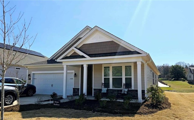 craftsman house with a porch, an attached garage, stone siding, and concrete driveway