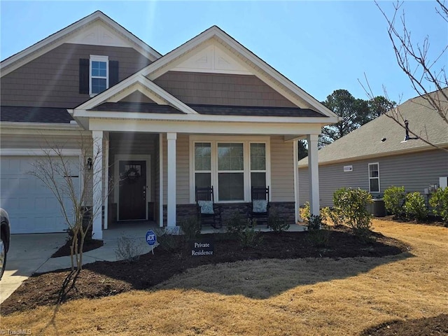 craftsman-style home featuring a porch, stone siding, an attached garage, and concrete driveway