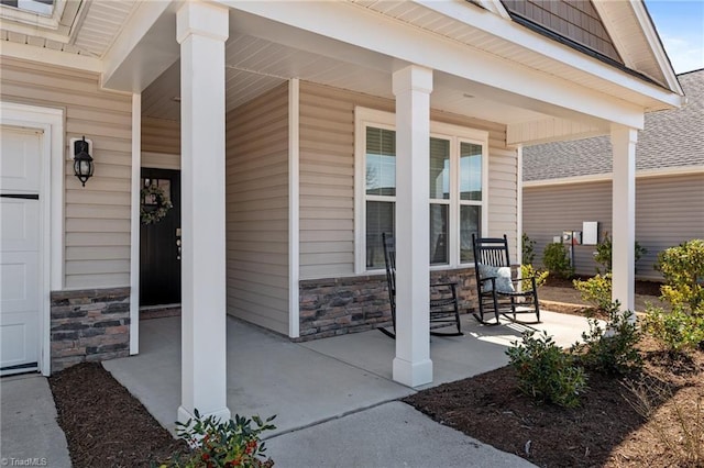 entrance to property with a garage, covered porch, and stone siding