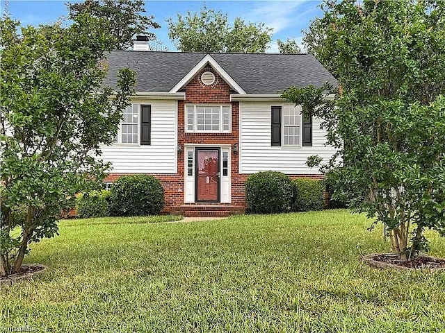 split foyer home featuring brick siding, roof with shingles, a chimney, entry steps, and a front lawn