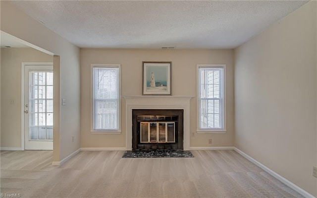 unfurnished living room featuring a wealth of natural light, light colored carpet, and a textured ceiling