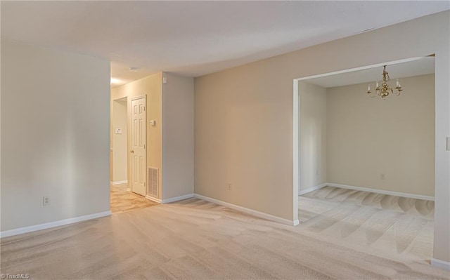 carpeted spare room featuring an inviting chandelier