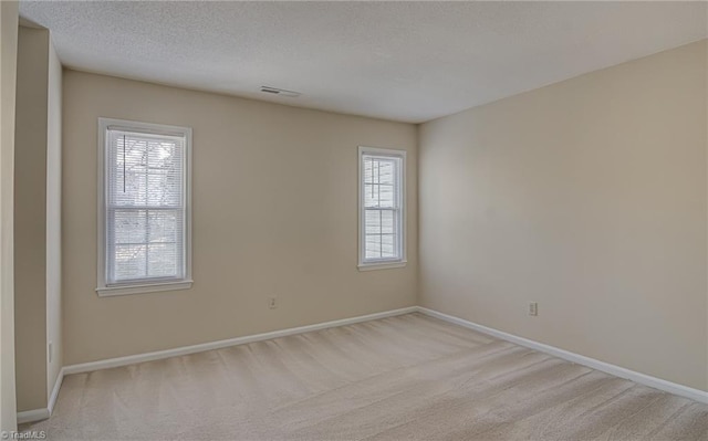 carpeted spare room with a textured ceiling