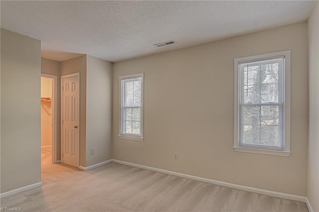 unfurnished room featuring light carpet and a textured ceiling