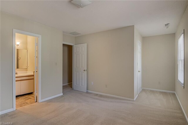 unfurnished bedroom with light colored carpet and ensuite bathroom