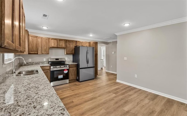 kitchen with light hardwood / wood-style flooring, appliances with stainless steel finishes, sink, light stone countertops, and ornamental molding