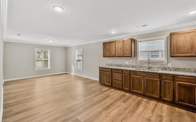 kitchen with sink, crown molding, light stone countertops, and light hardwood / wood-style floors