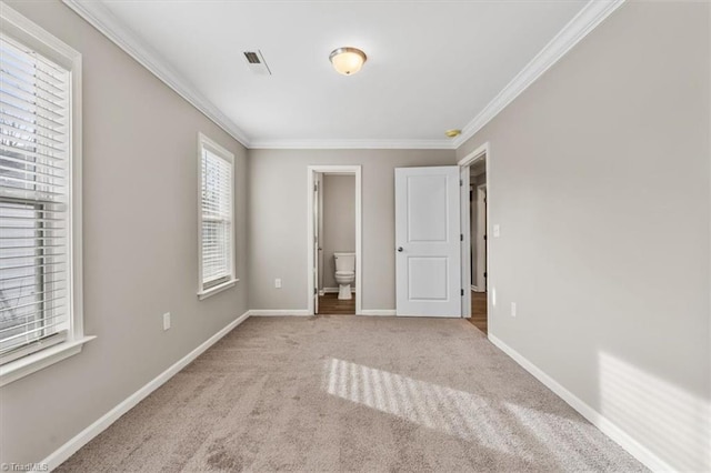 unfurnished bedroom with ornamental molding, light carpet, and ensuite bathroom