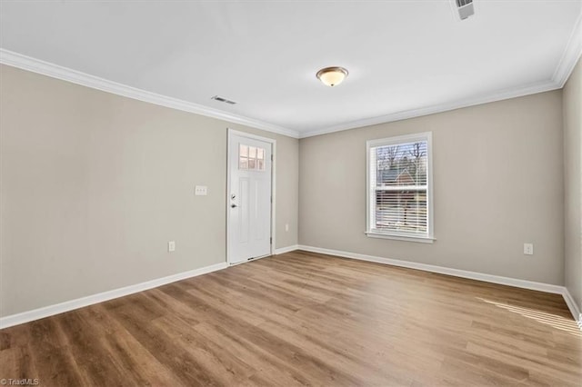 spare room featuring light wood-type flooring and crown molding