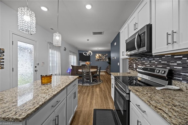 817 Sagemount St, Jamestown, NC 27282 - kitchen featuring appliances with stainless steel finishes, dark wood-type flooring, a chandelier, decorative backsplash, and a kitchen island