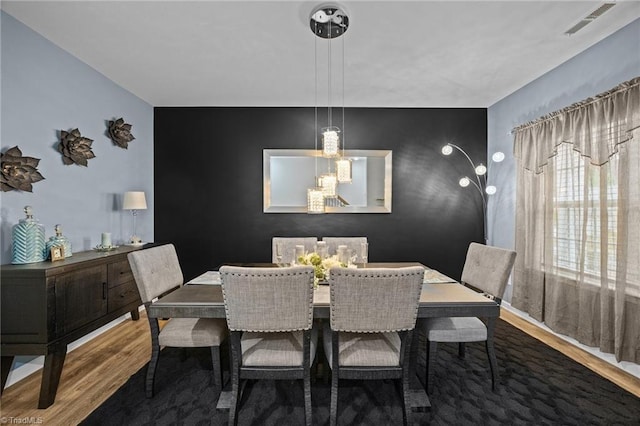 817 Sagemount St, Jamestown, NC 27282 - dining space with wood finished floors, an accent wall, and a chandelier