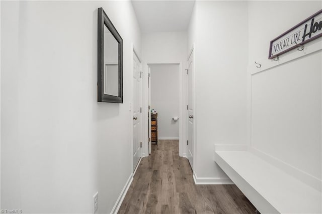 hall featuring dark wood-type flooring and baseboards