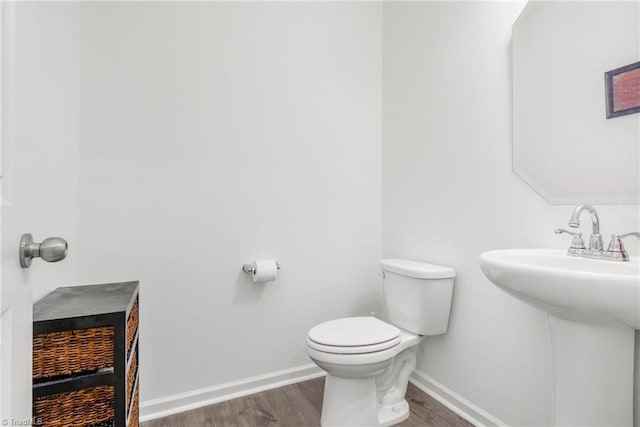 half bath with wood finished floors, toilet, and baseboards