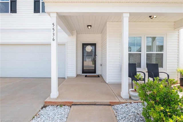 entrance to property with a porch, a garage, and driveway