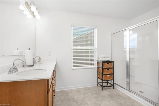 full bathroom with a stall shower, double vanity, and baseboards