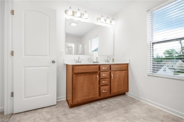 full bath featuring double vanity, a shower stall, and baseboards