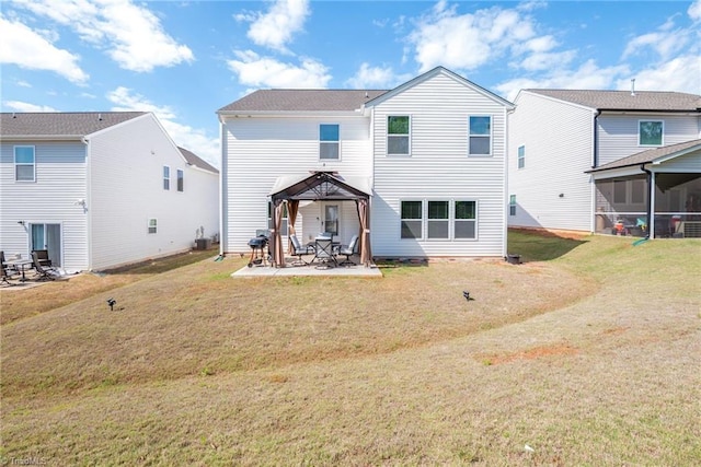 rear view of property featuring a gazebo, a lawn, a sunroom, and a patio area