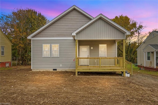 back house at dusk featuring covered porch