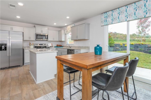 kitchen featuring light hardwood / wood-style floors, gray cabinetry, appliances with stainless steel finishes, and a center island