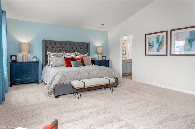 bedroom featuring ensuite bathroom, light carpet, and vaulted ceiling