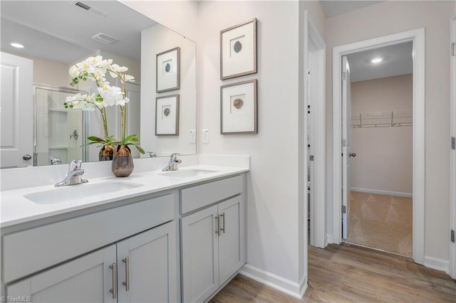 bathroom featuring vanity, wood-type flooring, and a shower with shower door