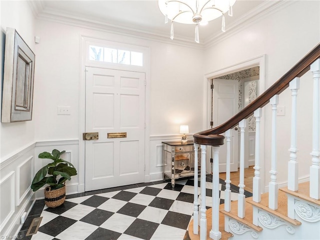 entrance foyer with dark floors, a decorative wall, crown molding, stairway, and an inviting chandelier