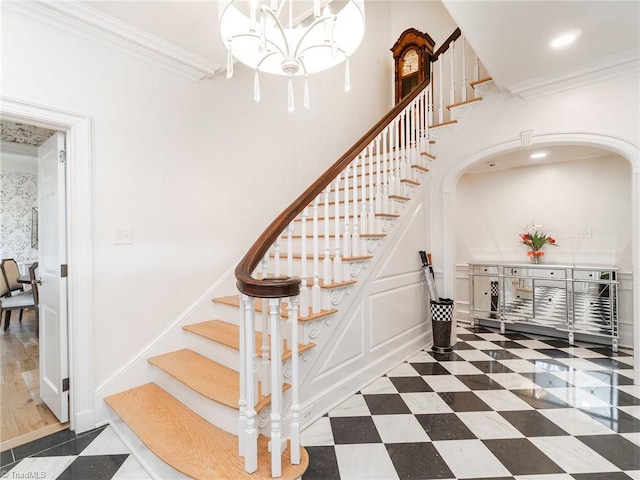 stairs with ornamental molding, a decorative wall, recessed lighting, and an inviting chandelier