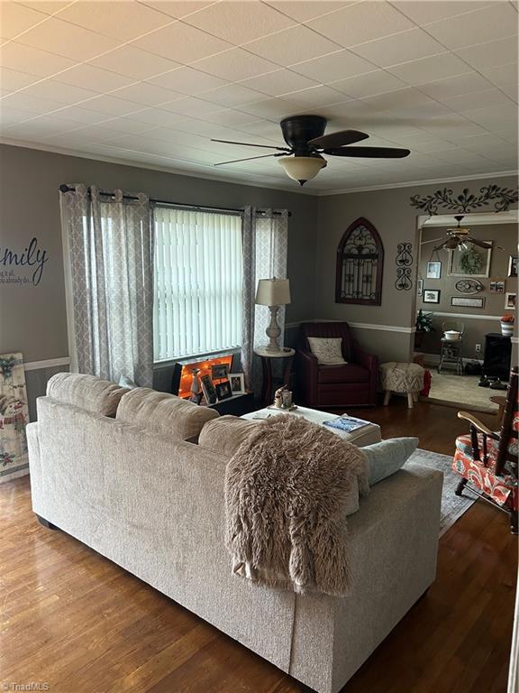 living room with hardwood / wood-style flooring, ornamental molding, and ceiling fan