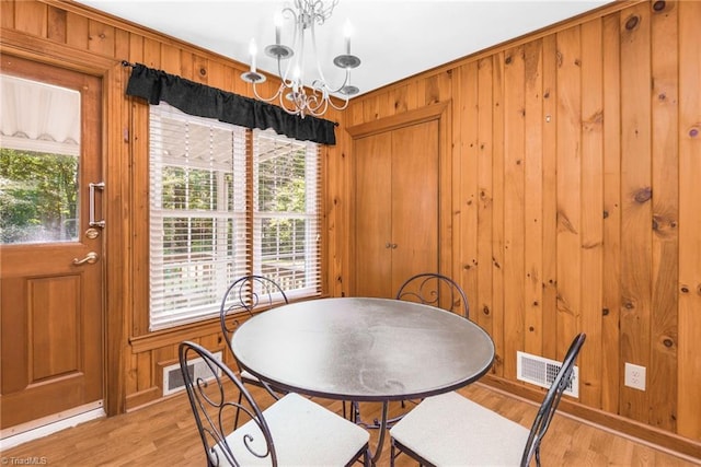 4750 Carlton Dr, Winston-Salem, NC 27105 - dining area with wood walls, healthy amount of natural light, light wood-type flooring, and a chandelier