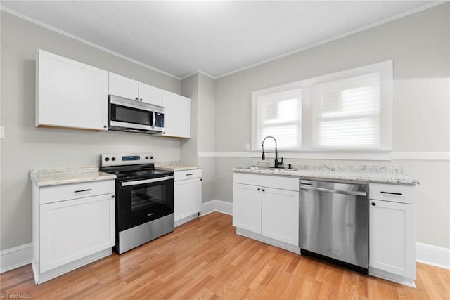 kitchen featuring crown molding, stainless steel appliances, white cabinetry, sink, and light hardwood / wood-style floors