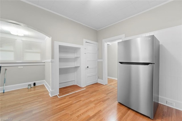 kitchen featuring stainless steel refrigerator, ornamental molding, and wood-type flooring