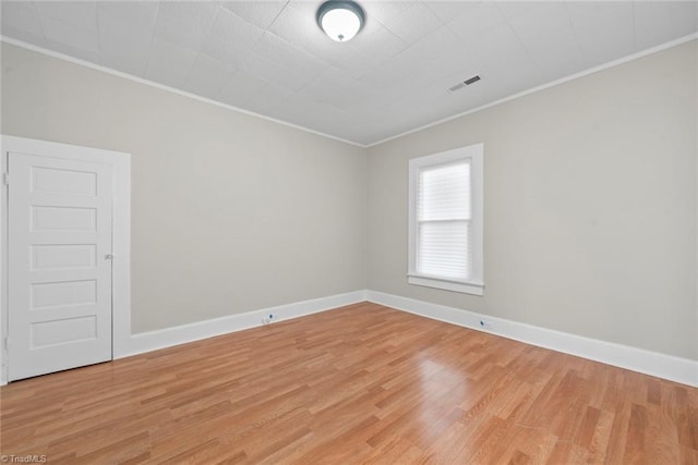 spare room with ornamental molding and light hardwood / wood-style flooring