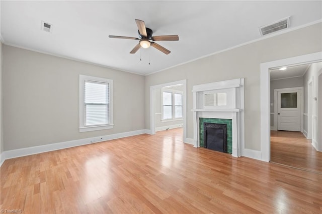 unfurnished living room with a tiled fireplace, light hardwood / wood-style floors, ceiling fan, and crown molding