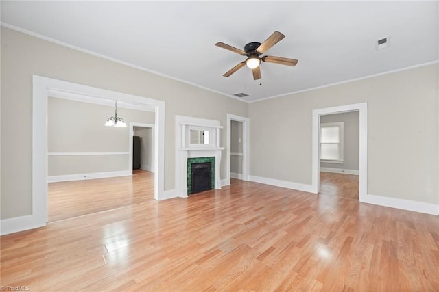 unfurnished living room featuring ornamental molding, ceiling fan with notable chandelier, and light hardwood / wood-style flooring