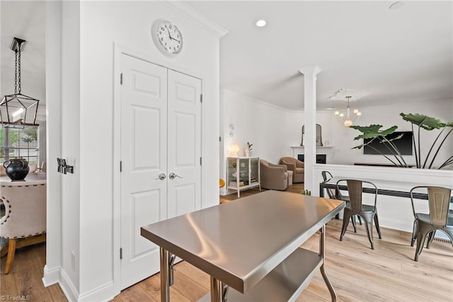 dining space with light wood-style floors, baseboards, ornamental molding, and a chandelier