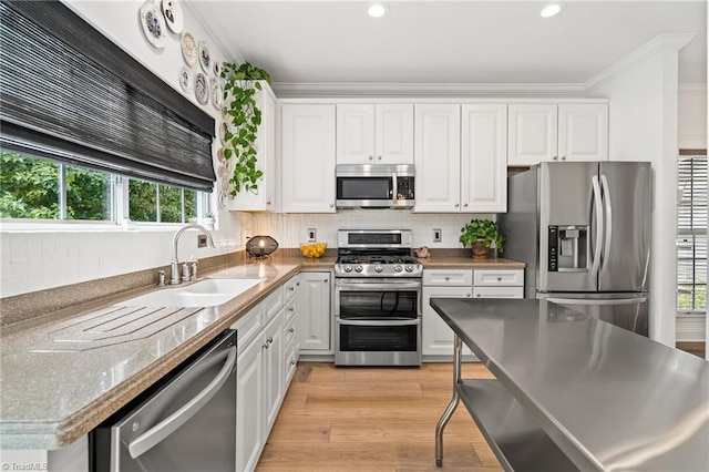 kitchen featuring white cabinetry, appliances with stainless steel finishes, a wealth of natural light, and a sink