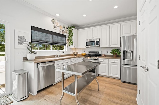 kitchen featuring crown molding, stainless steel appliances, plenty of natural light, and a sink