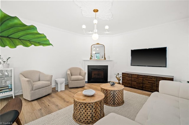 living area with crown molding, a fireplace, a chandelier, baseboards, and wood finished floors