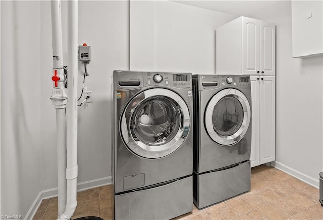 clothes washing area featuring cabinet space, separate washer and dryer, baseboards, and light tile patterned flooring