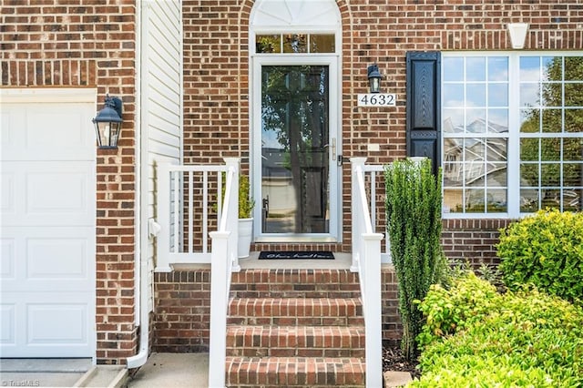 entrance to property featuring a garage and brick siding