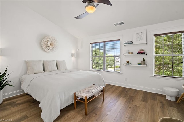 bedroom featuring baseboards, visible vents, wood finished floors, and vaulted ceiling