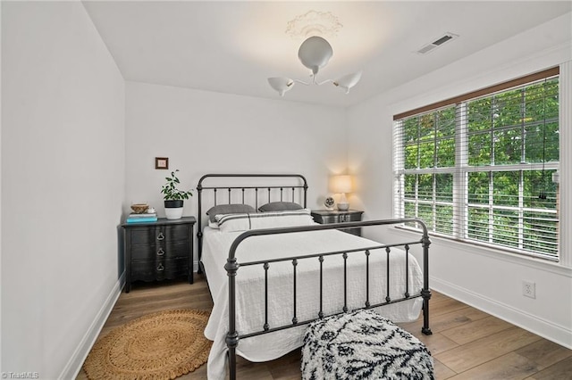 bedroom with baseboards, wood finished floors, and visible vents