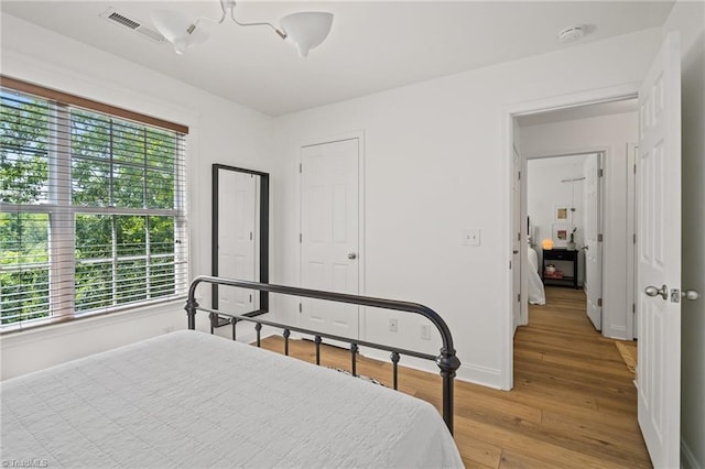 bedroom with baseboards, light wood-style flooring, and visible vents