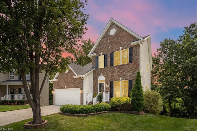 traditional home with a garage, a yard, concrete driveway, and brick siding