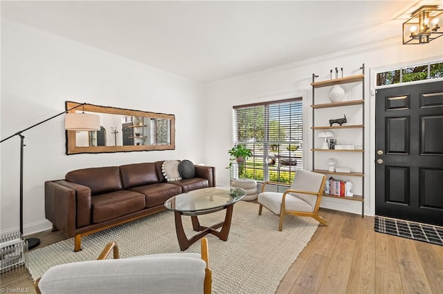 living room featuring crown molding, baseboards, an inviting chandelier, and light wood finished floors