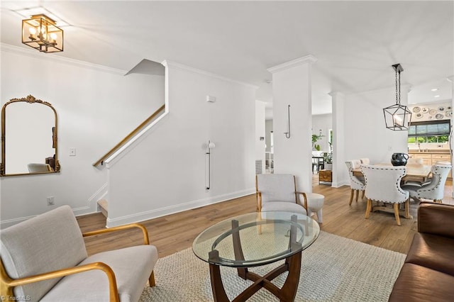 living room with an inviting chandelier, ornamental molding, wood finished floors, and stairway