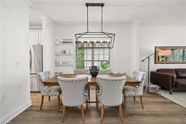 dining space with crown molding, an inviting chandelier, and wood finished floors